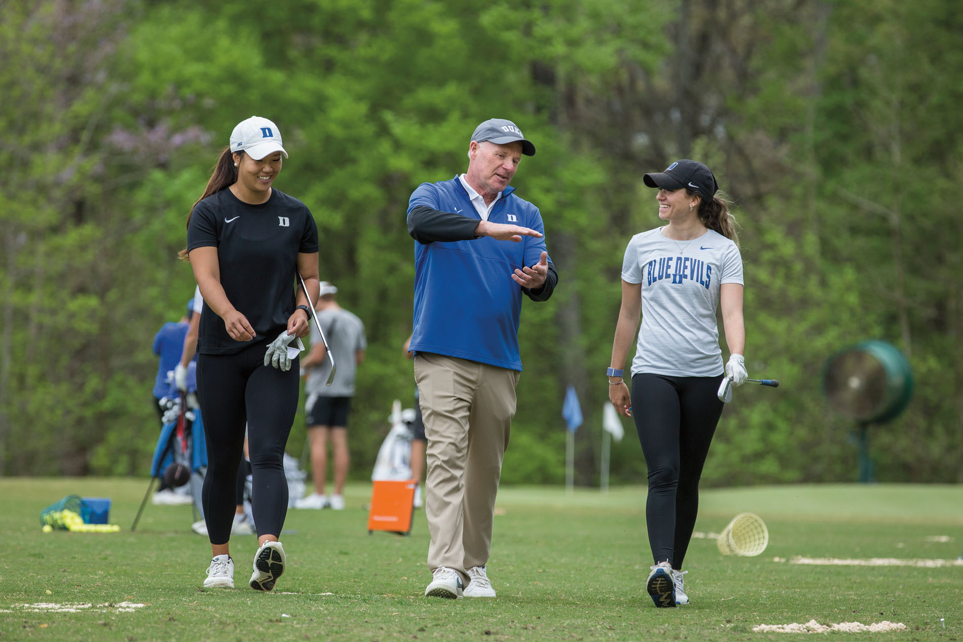 Dan Brooks works with women's golf team members Anne Chen, left, and Andie Smith.