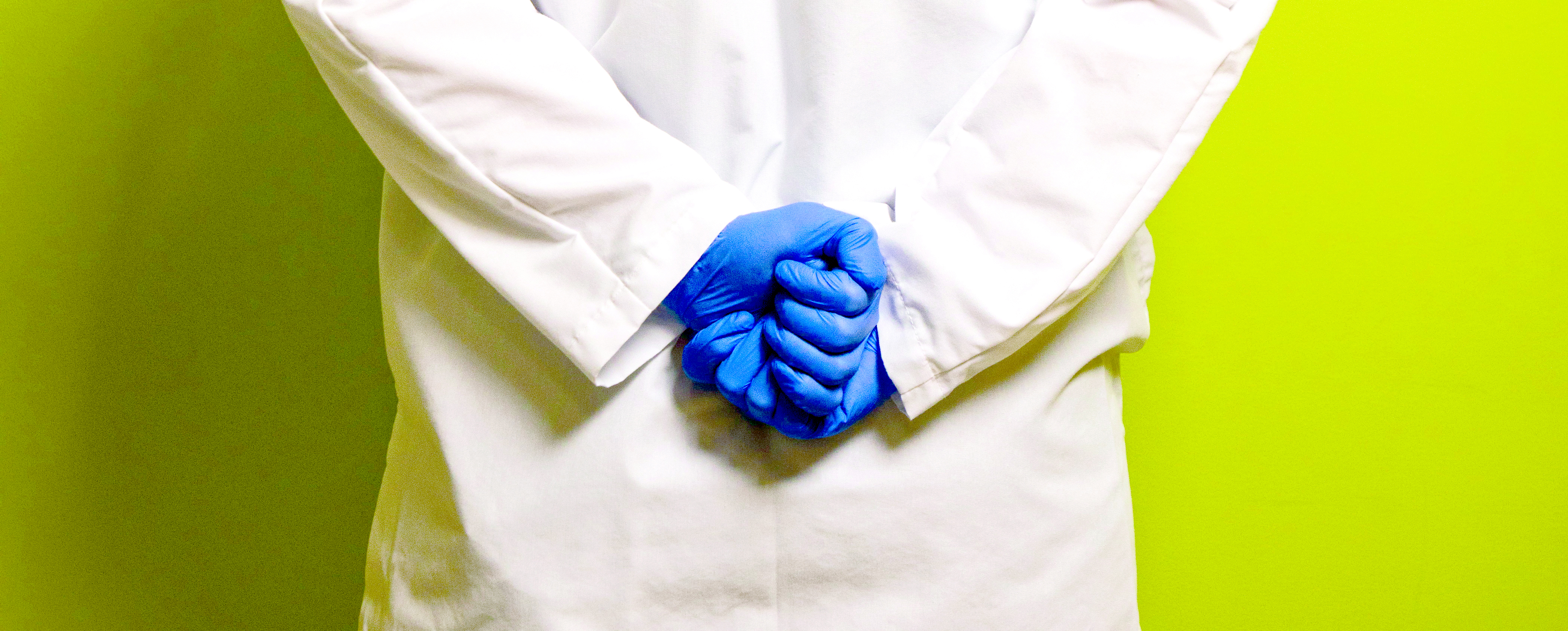 Person in white coat with blue vinyl gloves