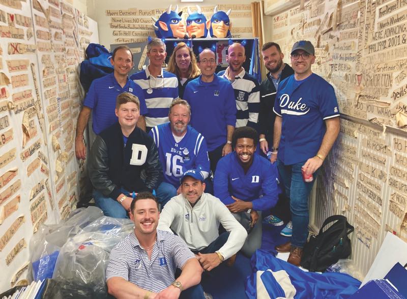The hundredth anniversary brought Blue Devils back to campus and to the storeroom where they keep old headbands – and heads. Front row: Stratton Thomas ’22, left, and Al Cohn ’95. Middle row, from left: Ross Winston ’19, Jeep Wedding ’90, Billy Gist ’19. Back row, from left: Steve O’Brien ’87, Harold Beaty ’84, Lisa Weistart ’92, Patrick Hunnicutt ’96, David Schmidt ’07, Graham Sharpe ’11, Russell Crock ’15.