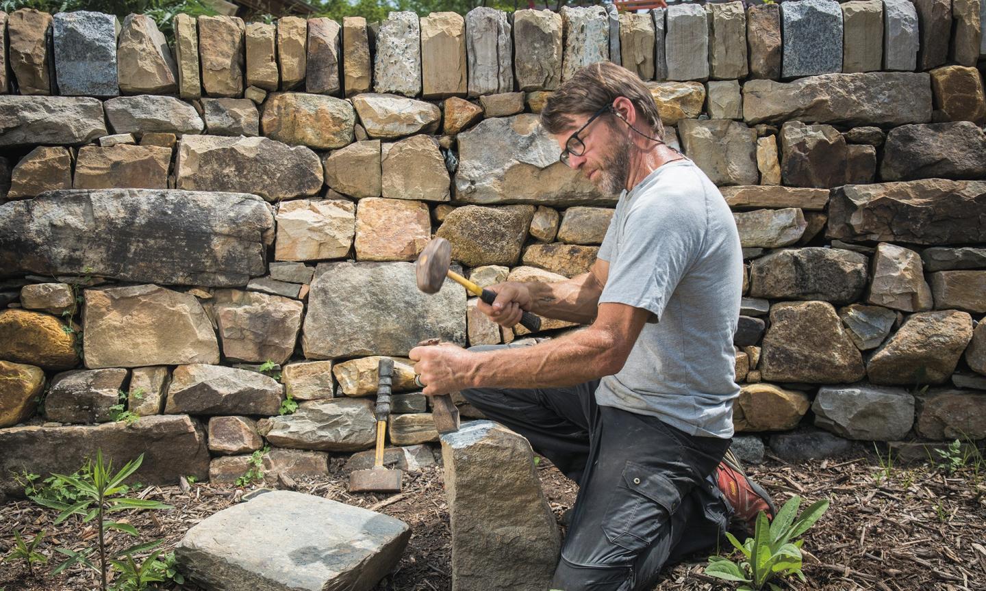 Burleson at work on a dry-laid stone wall in Duke Gardens.
