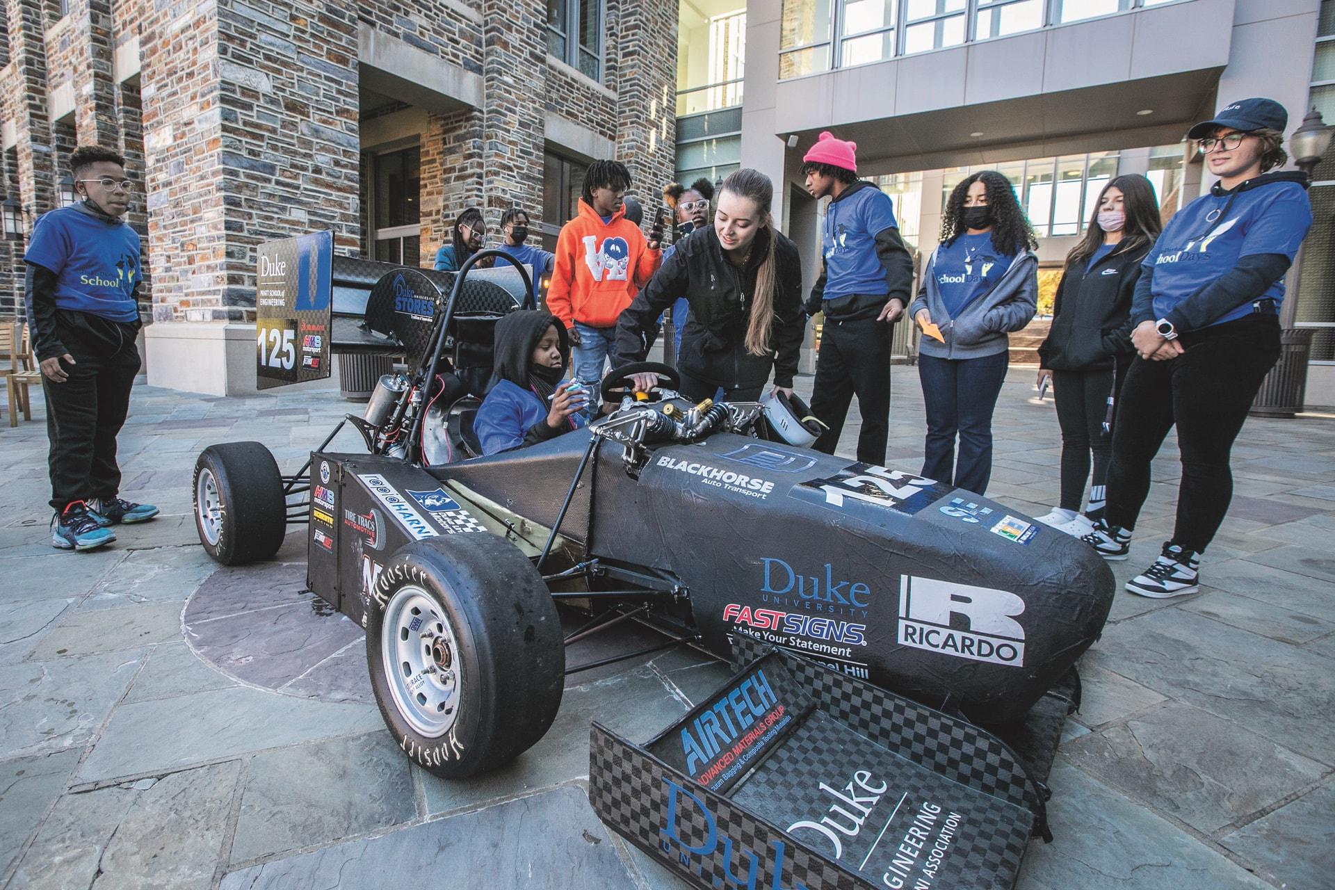 THUMBNAIL: Local schoolchildren attending Duke's "School Days" presentation get a close-up tour of the Pratt School of Engineering race team car from its driver, Alexandra Gray.